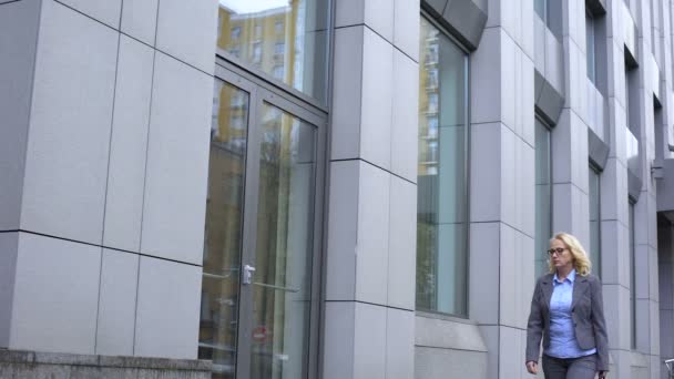 Triest leeftijd vrouw op zoekvenster glas reflectie, wandelen langs kantoorgebouw — Stockvideo