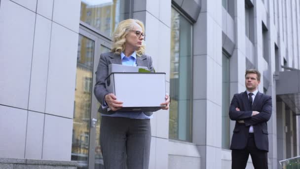 Young Business man kijkt naar ontslagen leeftijd dame verlaten van kantoor, competitie — Stockvideo