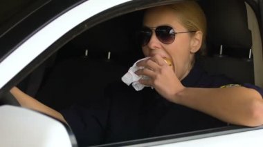 Bayan polis devriye arabasında hamburger yiyor, sağlıksız atıştırmalık, sindirim sorunları riski