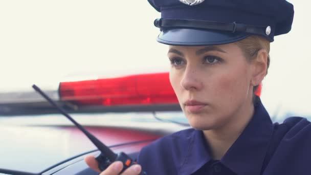 Serious police lady accepting call and getting into patrol car, ready for action — Stock Video