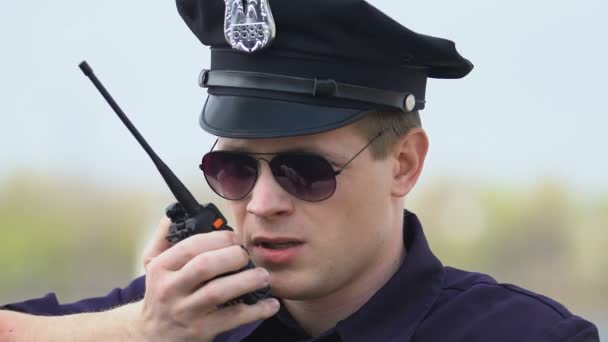 Oficial de patrulla masculino hablando por radio, transmitiendo información sobre delincuentes — Vídeo de stock