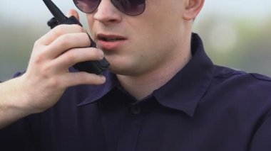 Erkek polis memuru radyo setinde konuşuyor, bilgi alışverişinde, takım çalışması
