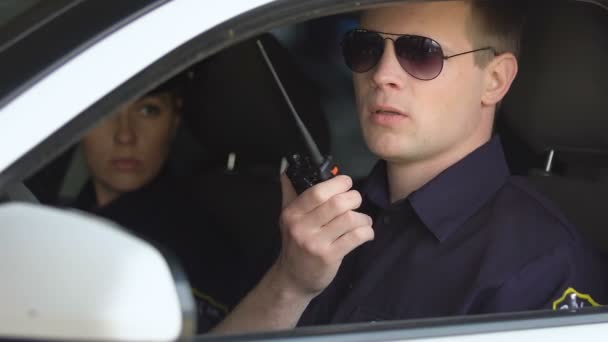 Male and female cops sitting in patrol car accepting emergence call, enforcement — Stock Video