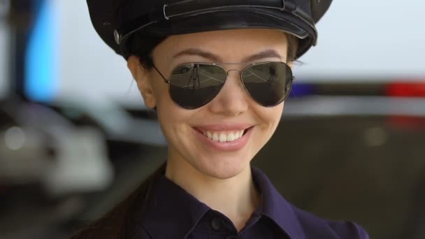 Amistosa señora patrulla asiática en gorra y gafas de sol sonriendo a la cámara, protección — Vídeos de Stock