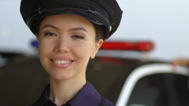 Молода приваблива патрульна леді посміхається до камери, професійні поліцейські — стокове відео