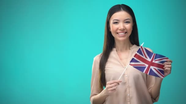 Leende kvinna som innehar Storbritannien flagga, redo att lära sig främmande språk — Stockvideo
