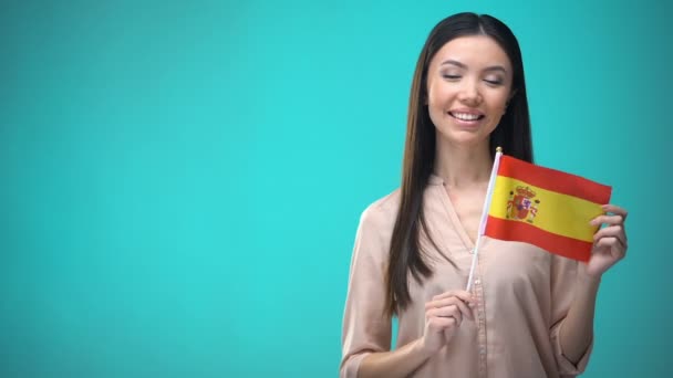 Весела дівчинка тримає прапор Іспанії готовий вивчати іноземну мову, іспанську школу — стокове відео