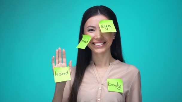 Estudiante femenina aprendiendo inglés, cubierta con partes del cuerpo notas adhesivas, educación — Vídeos de Stock