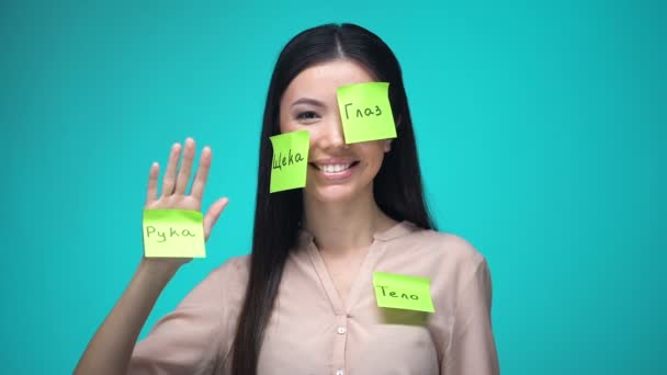 Vrouwelijke student leren Russisch, bedekt met lichaamsdelen Sticky Notes, onderwijs — Stockvideo