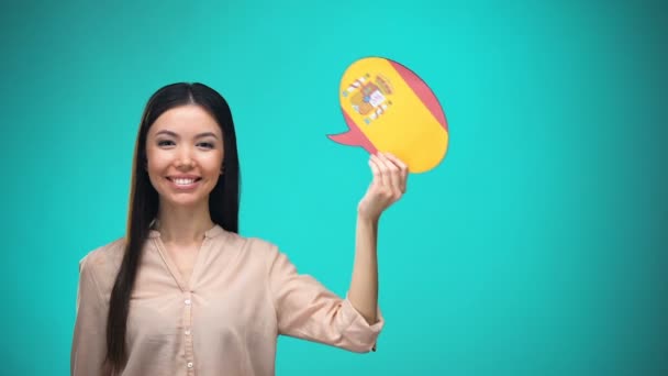 Menina sorridente segurando bandeira espanhola fala bolha, aprendendo idioma, ideias de viagem — Vídeo de Stock