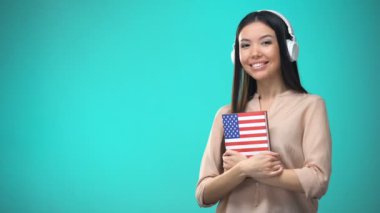 Kız öğrenci kulaklık amerikan İngilizce ses dersleri dinleme, elinde kitap