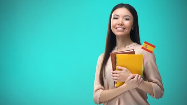 Mujer alegre sosteniendo el libro de la bandera de España, educación en el extranjero, aprendizaje de idiomas — Vídeos de Stock