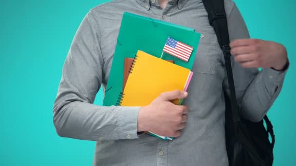 Student trzyma notebooki z flagą USA, Międzynarodowy program edukacyjny — Wideo stockowe