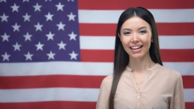 Gülen kadın Abd bayrağı arka plan, göç karşı thumbs-up işareti gösteren