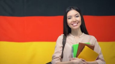 Mutlu kız öğrenci Alman bayrağı arka plan, eğitim karşı copybooks tutan
