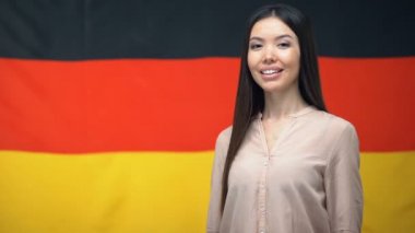 Alman bayrağı arka plan karşı thumbs-up işareti gösteren güzel Asyalı kadın