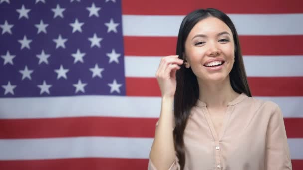 Mujer asiática positiva de pie contra el fondo de la bandera de EE.UU., día de la independencia — Vídeo de stock