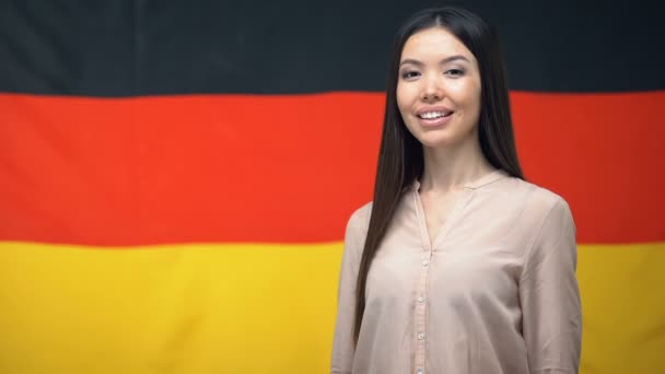 Красивая азиатская женщина показывает большой палец вверх знак на фоне немецкого флага — стоковое видео