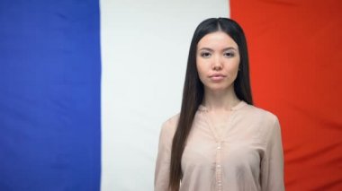 Ciddi Asyalı kadın Fransız bayrağı arka plan, elçilik karşı pasaport gösteren