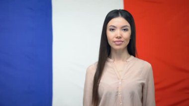 Fransız bayrağı arka plan karşı kredi kartı tutan Asyalı kadın, para transferi