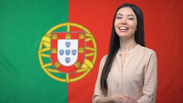 Mujer sonriente de pie con las manos cruzadas sobre fondo de bandera portuguesa — Vídeo de stock