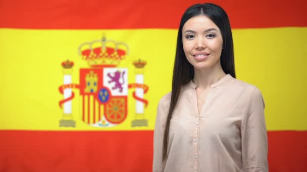 Mujer asiática sonriente mostrando un gesto de pulgar hacia arriba contra el fondo de la bandera española — Vídeo de stock