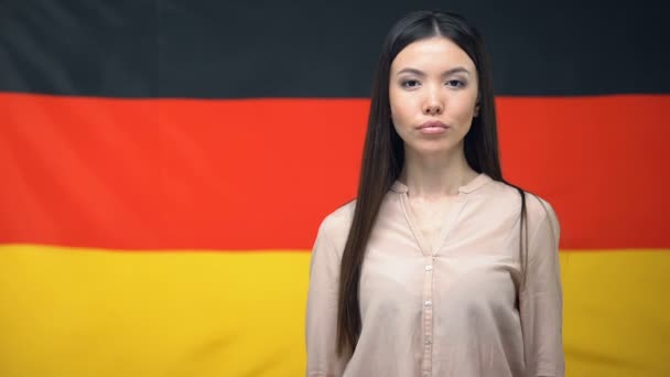 Serious Asian kobieta pokazując paszport przeciwko niemiecki flaga tło, zbliżenie — Wideo stockowe