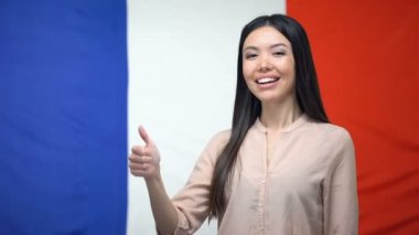 Mutlu Asyalı kadın Fransız bayrağı arka plan, şablon karşı thumbs-up gösteren