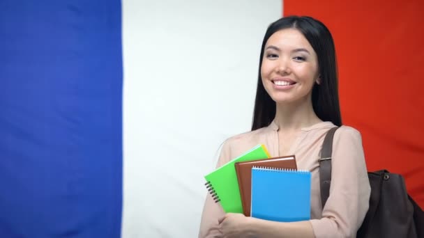 Vrouwelijke student bezit copybooks tegen Franse vlag, internationaal onderwijs — Stockvideo