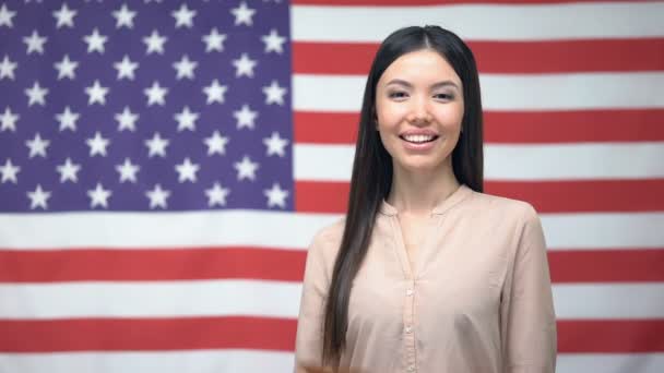 Mulher adorável mostrando passaporte contra fundo bandeira dos EUA, cidadania — Vídeo de Stock