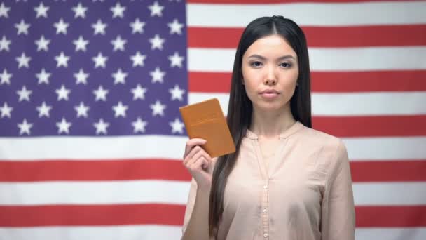 Fiduciosa donna asiatica che mostra il passaporto sullo sfondo della bandiera USA, migrazione — Video Stock