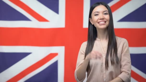 Усміхнена Азіатська жінка стоїть проти британського прапора, Міжнародна дружба — стокове відео
