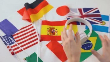 Kulaklığı alan eller, masada farklı ülkeler bayrakları, dil ses dersleri