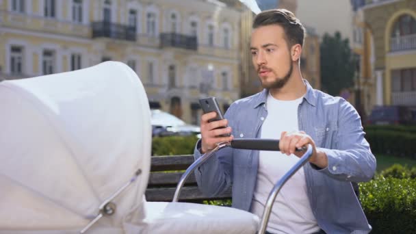 Homme heureux utilisant un smartphone près d'un landau, surpris par une application mobile facile — Video