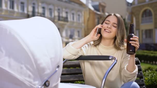 Donna spensierata parlando telefono, bevendo birra e dondolando carrozzina, ignorare — Video Stock