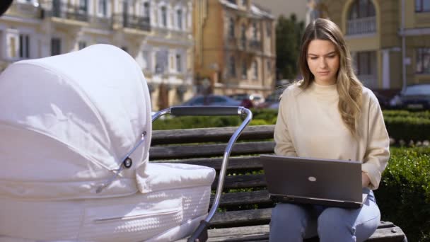 Irriterad kvinnlig frilansare arbetar försöker lugna ner gråtande bebis i sittvagn — Stockvideo