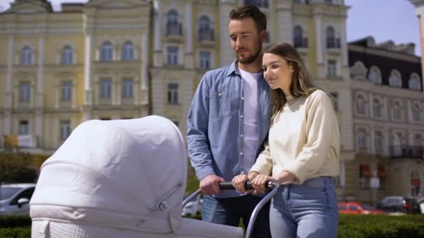 Giovane uomo e donna guardando il bambino oscillante carrozza, amore familiare, abbracci — Video Stock