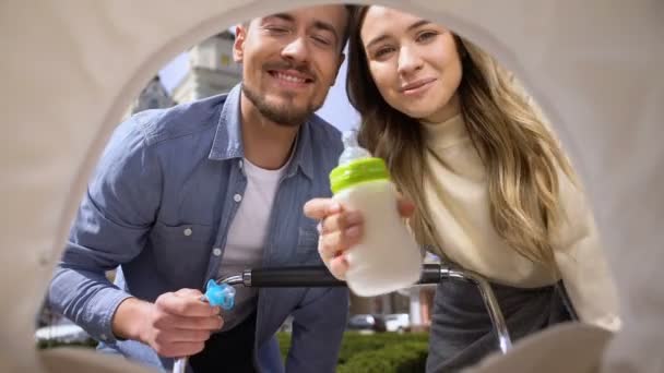 Счастливый мужчина и женщина кормят ребенка бутылкой молока, родительской привязанностью, любовью — стоковое видео