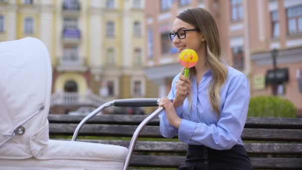 Moderne junge Frau im Büroanzug spielt mit neugeborener Kutsche und hält Rassel — Stockvideo