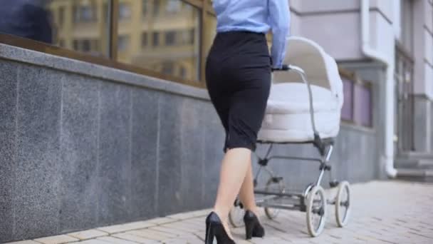 Young mom in suit pushing pram going to business center, family and career — Stock Video