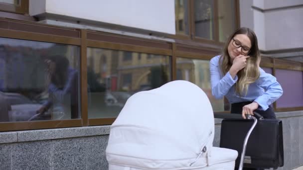 Stressed office employee swinging baby carriage and talking phone, multitasking — Stock Video