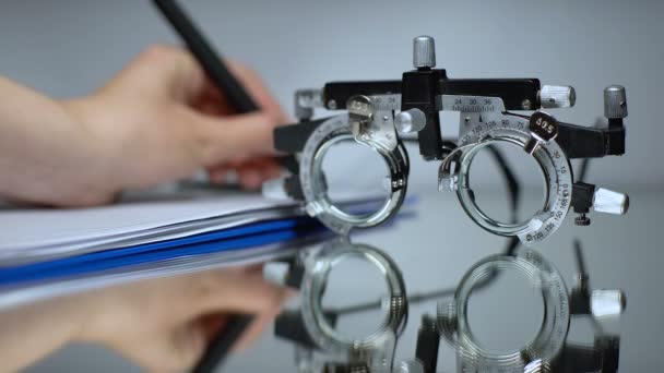 Arzt schreibt Brillenrezept, Sehkontrolle mit optischem Testrahmen — Stockvideo