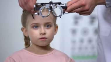 Optometrist küçük kız özel gözlük koyarak, Tembel göz hastalığı tanısı