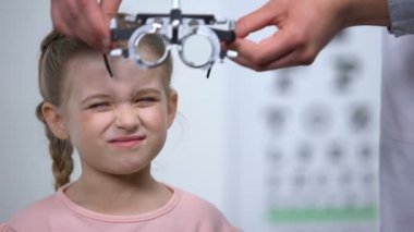 Doktor miyopi tanısı için çocuk üzerinde optik deneme çerçevesi giyen, bulanık görme