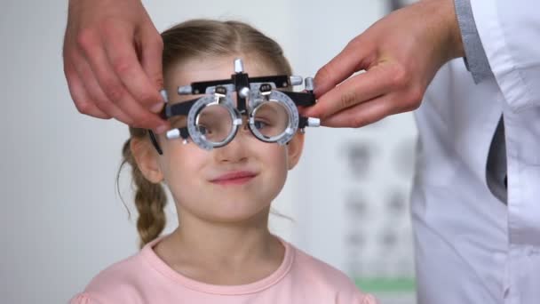 Optometrist putting phoropter on little girl, child complaining to see nothing — Stock Video