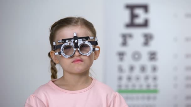 Çocuk oftalmolojik klinikte phoropter ile gözleri inceleyen Pretty kız — Stok video