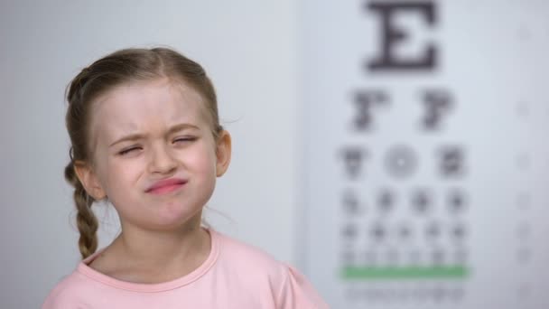 Küçük kız göz grafiğinden harfleri okumaya çalışıyor, yakın görüşlülük tanısı — Stok video