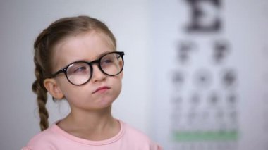 Gözlük takan pensive akıllı kız, klinikte göz grafiği ile görme testi