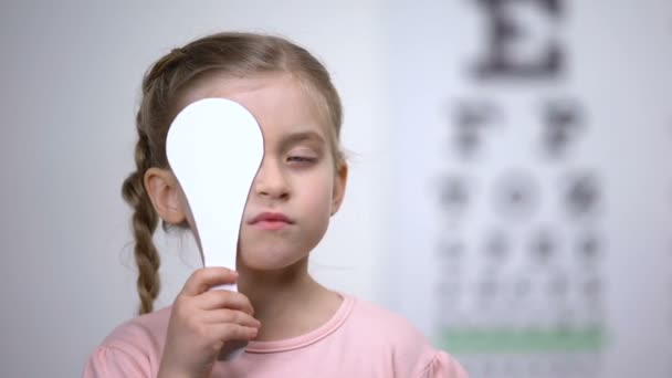 Закрытие глаза дошкольницы для полного обследования зрения, диагностики зрения — стоковое видео