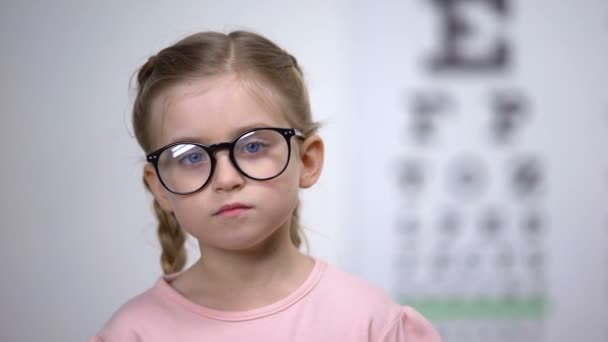 Hübsches Mädchen mit Brille, das die Augen schließt und eine Sehuntersuchung in der Augenklinik macht — Stockvideo